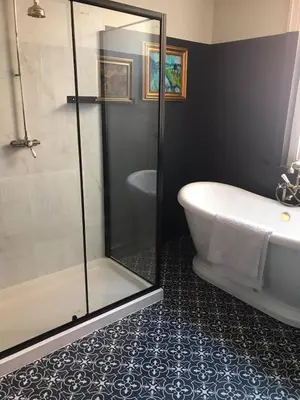 a bathroom with a tub and a glass shower at Swan & Railway Hotel Wigan in Wigan