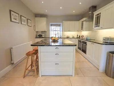 a kitchen with white cabinets and a black counter top at Clock Tower in Grange Over Sands