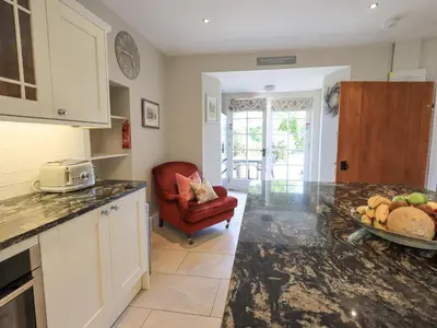 a kitchen with a red chair and a table with a bowl of fruit at Clock Tower in Grange Over Sands