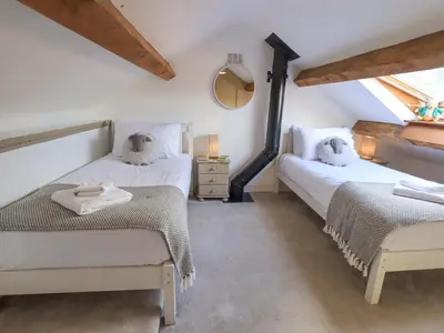 two twin beds in a room with a window at Clock Tower in Grange Over Sands