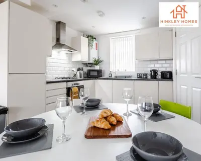 a kitchen with a table with wine glasses and croissants at Newbuild 4bed - City Centre - Free secure parking! By Hinkley Homes Short Lets & Serviced Accommodation in Liverpool