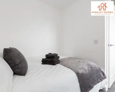 a bed with a pile of black towels on it at Newbuild 4bed - City Centre - Free secure parking! By Hinkley Homes Short Lets & Serviced Accommodation in Liverpool