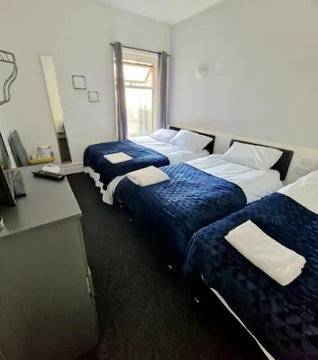 a hotel room with three beds and a desk at The Bosworth House Hotel in Blackpool