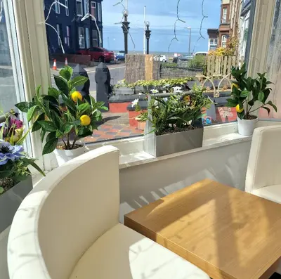 a room with a table and a window with plants at The Bosworth House Hotel in Blackpool