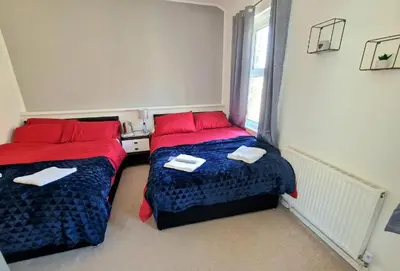 a bedroom with two beds with red pillows and a window at The Bosworth House Hotel in Blackpool