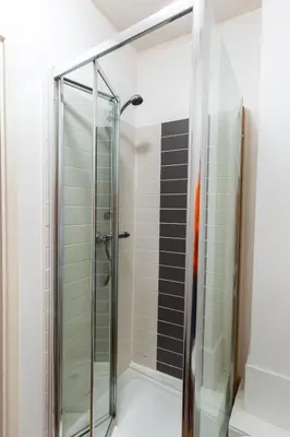 a glass shower in a bathroom with black and white tiles at Cosy Studio in Merseyside in Great Location in Liverpool