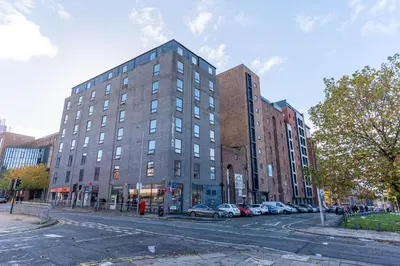 a tall building on a city street with parked cars at Cosy Studio in Merseyside in Great Location in Liverpool