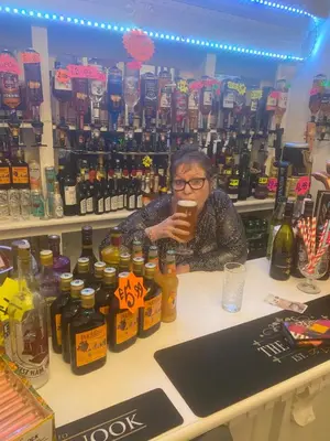 a woman sitting at a counter in a liquor store at The Cosy Nook in Blackpool