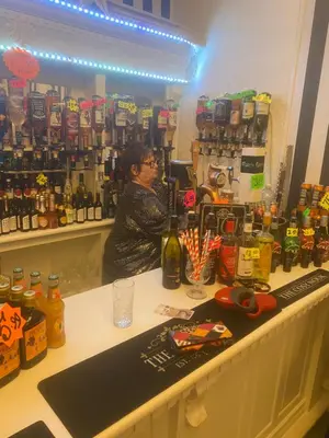 a woman standing behind a counter in a liquor store at The Cosy Nook in Blackpool