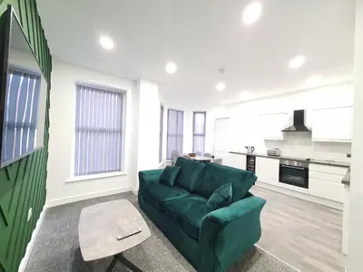 a living room with a green couch and a kitchen at DYSA Banks Apartments in Blackpool
