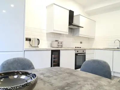 a kitchen with a table and chairs and white cabinets at DYSA Banks Apartments in Blackpool