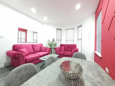 a living room with a table and pink furniture at DYSA Banks Apartments in Blackpool