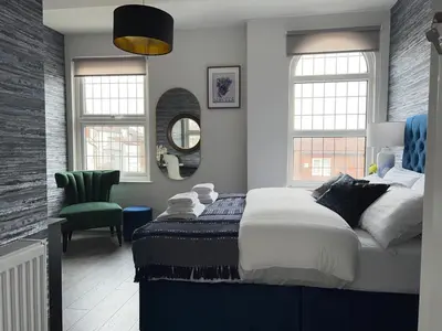 a bedroom with a large bed and a green chair at Room 4 (8 Holland Street) in Liverpool