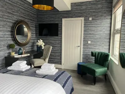 a bedroom with a bed and two chairs and a mirror at Room 4 (8 Holland Street) in Liverpool