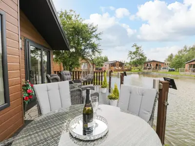 a bottle of wine sitting on a table on a patio at Loluke Lodge on The Lake in Carnforth