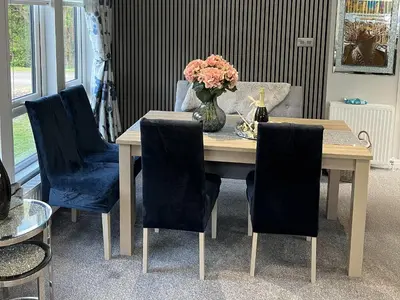 a dining room table with chairs and a vase of flowers at Loluke Lodge on The Lake in Carnforth