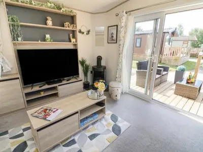 a living room with a television and a sliding glass door at Langdale Lodge in Carnforth