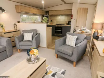 a living room with two chairs and a kitchen at Langdale Lodge in Carnforth