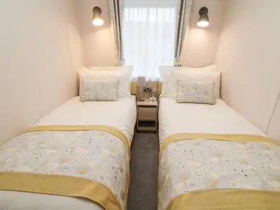 two beds in a small room with a window at Langdale Lodge in Carnforth