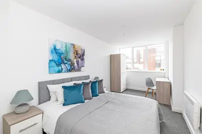 a white bedroom with a large bed with blue pillows at Winkley House by Guestz in Preston