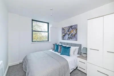 a white bedroom with a bed with blue pillows at Winkley House by Guestz in Preston