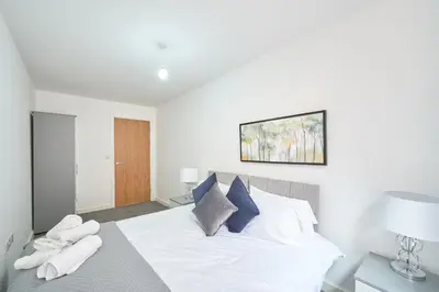 a bedroom with a bed with white sheets and blue pillows at Winkley House by Guestz in Preston