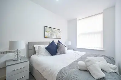 a white bedroom with a bed and a window at Winkley House by Guestz in Preston