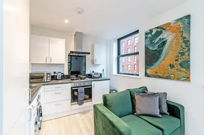 a living room with a green couch in a kitchen at Winkley House by Guestz in Preston