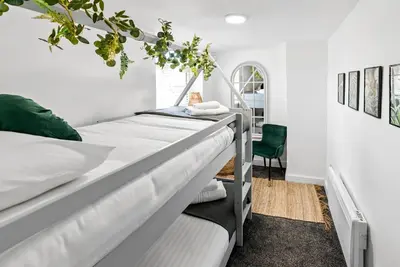 a bedroom with two beds and a green chair at The Treehouse at The Hideaway STAMP SA in Blackpool