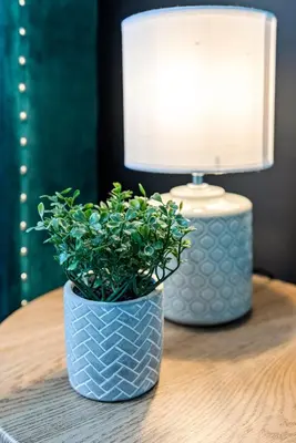 a table with a lamp and a blue vase with a plant at The Treehouse at The Hideaway STAMP SA in Blackpool