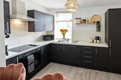 a kitchen with black cabinets and a sink at The Nest at The Hideaway STAMP SA in Blackpool