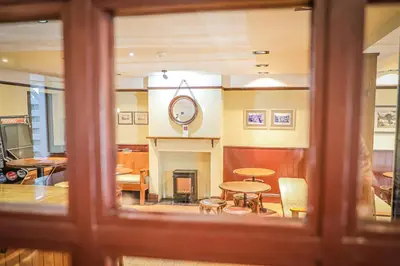a room with a fireplace and a table and chairs at Hope and Anchor in Flookburgh