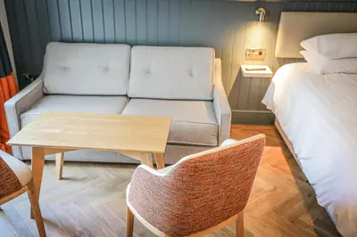 a living room with a couch and a table next to a bed at Hope and Anchor in Flookburgh