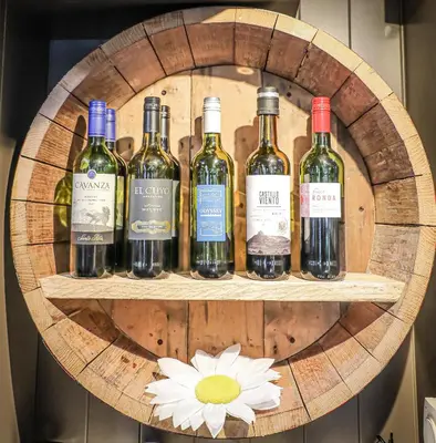 a bunch of wine bottles on a shelf with a flower at Hope and Anchor in Flookburgh