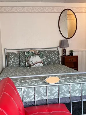 a bedroom with a bed with a mirror and a red chair at Galaxy Hotel in Blackpool