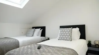 two beds in a room with white walls at The Kop End Penthouse in Liverpool