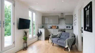 a living room with a couch and a kitchen at The Kop End Penthouse in Liverpool