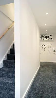 an empty hallway with stairs and a wall with a mural at The Kop End Penthouse in Liverpool