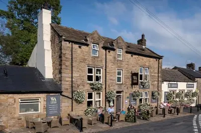an old stone building with people sitting outside of it at The Waddington Arms in Waddington
