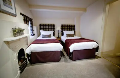 two beds in a room with a fireplace at The Waddington Arms in Waddington