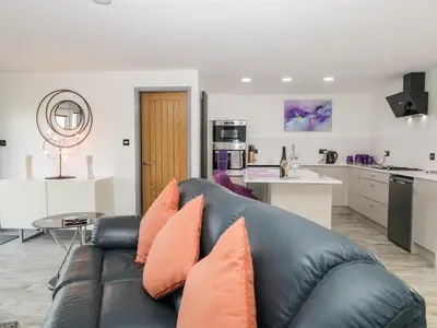 a living room with a black leather couch with orange pillows at The Annex in Ulverston