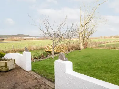 a garden with white fences and a green field at The Annex in Ulverston