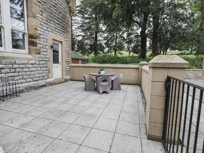 a patio with a table in front of a building at The Kennedy House Stone Cross Mansion in Ulverston