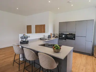 a kitchen with a island with chairs and a bowl of fruit on it at The Emma Suite Stone Cross Mansion in Ulverston