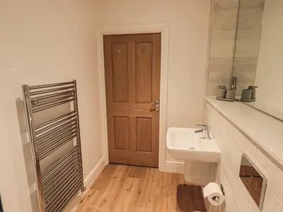 a bathroom with a sink and a wooden door at The Emma Suite Stone Cross Mansion in Ulverston
