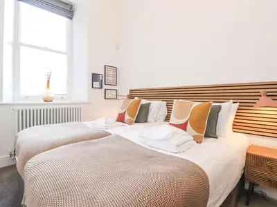 a bedroom with two beds and a window at The Wilfred Suite Stone Cross Mansion in Ulverston