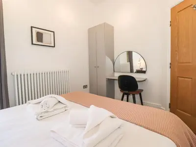 a bedroom with a bed with a mirror and a chair at The Wilfred Suite Stone Cross Mansion in Ulverston
