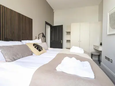 a bedroom with a large white bed with towels on it at The Mary Maude Suite Stone Cross Mansion in Ulverston