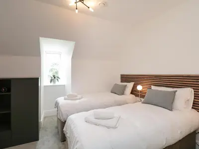 two beds in a room with white walls at William Tower Suite Stone Cross Mansion in Ulverston