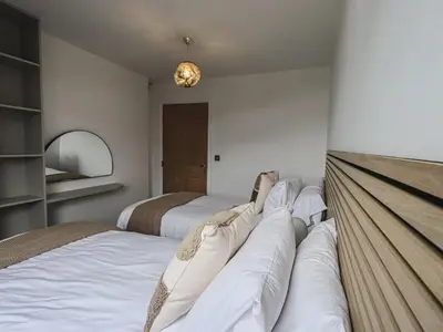 a bedroom with two beds and a chandelier at The Lucy Suite Stone Cross Mansion in Ulverston